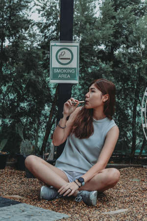Asian woman inhaling and cigarette vaping. Female secretly smoking in bathroom at home. Concept of quit smoking and anti cigarette.の写真素材