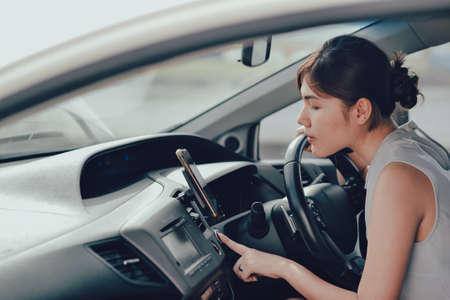 Relaxed happy petite woman hand pressing on car's engine start button. lifestyle and people concept.の写真素材