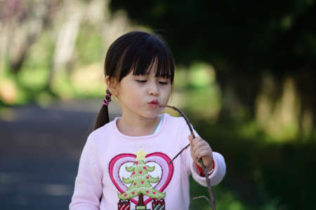 Happy young asian girl kissing a branchの写真素材