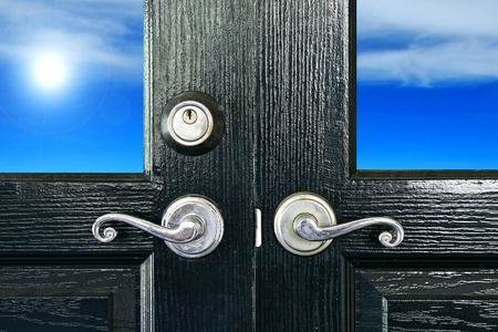 Door handles with an old double door have sun and sky backgroundの写真素材
