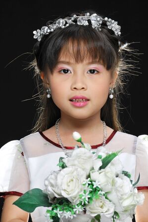 Happy smiling little girl with bouquet on black background in studio の写真素材