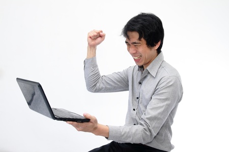 Businessman holding his fists in excitement while looking at laptopの写真素材