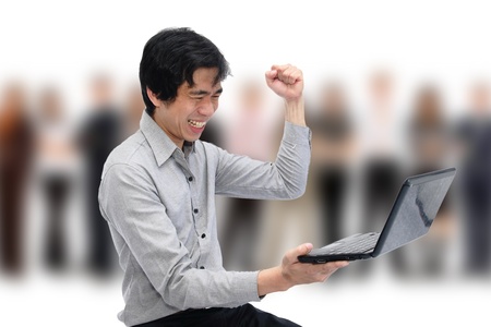 Businessman holding his fists in excitement while looking at laptopの写真素材