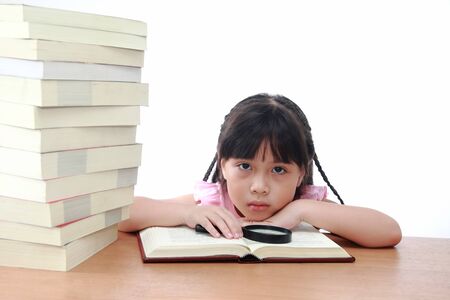 Beautiful little and serious asian girl reading book.の写真素材