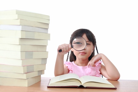 Asian little girl reading a book with magnifying glass isolated on a over white backgroundの写真素材