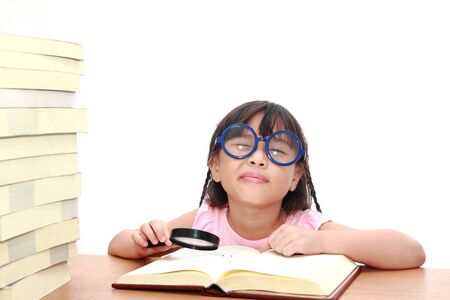 Asian little girl reading a book with magnifying glass isolated on a over white backgroundの写真素材