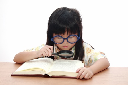 Asian little girl reading a book with magnifying glass isolated on a over white backgroundの写真素材