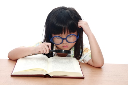 Asian little girl reading a book with magnifying glass isolated on a over white backgroundの写真素材