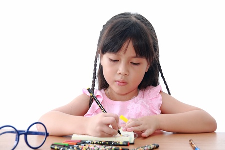 Asian little girl draw on a book isolated on a over white backgroundの写真素材