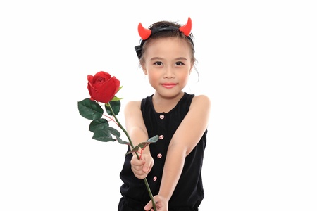 Scary cute little asian girl in black Halloween costume give red rose.の写真素材