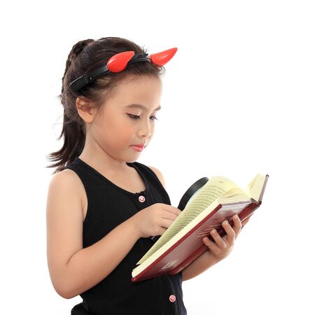 Beautiful little asian girl reading book with magnifying glassの写真素材