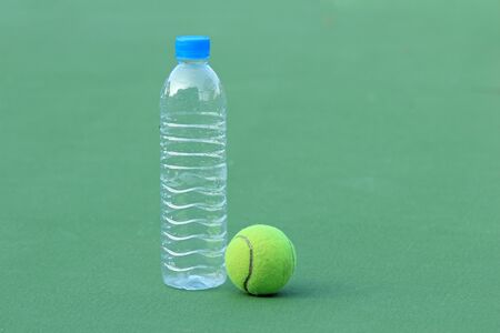 Tennis ball on tennis court with bottled drinking waterの写真素材