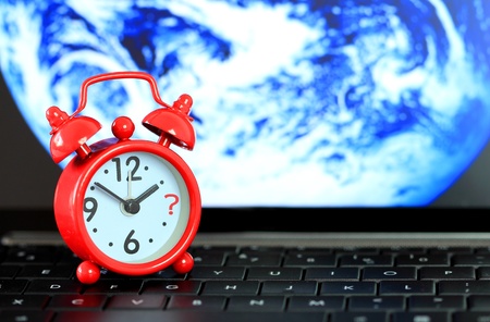 Red alarm clock on keyboard with earth background. When the end of the world.の写真素材
