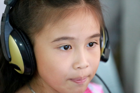 Little girl using laptop with headphone