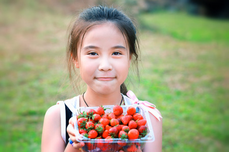 Little girl eating strawberriesの写真素材