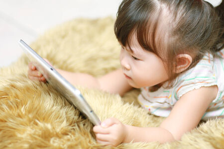 Happy baby girl using tablet computerの写真素材