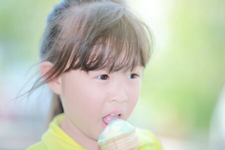 Cute little girl eating ice cream in summer day