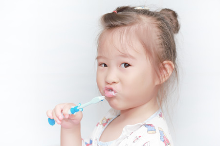 Little girl brushing her teeth on white backgroundの写真素材