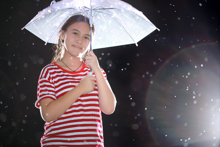 Cute little girl with a umbrella in the rainの写真素材