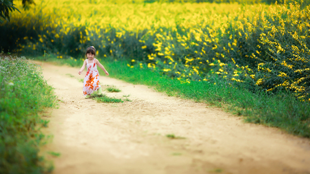 little girl running in flower fieldの写真素材