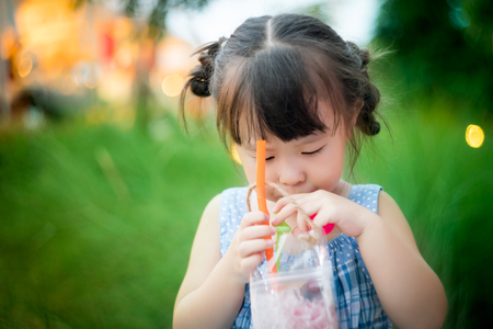 Little girl drinking water through a strawの写真素材