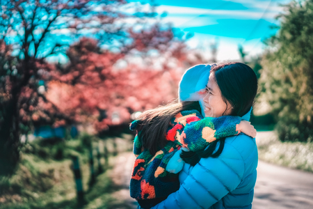 Mother and her little daughter with cherry blossom tree backgroundの写真素材