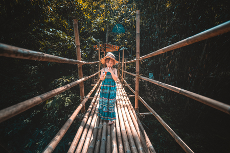 asian little girl  eating ice cream on bamboo bridgeの写真素材