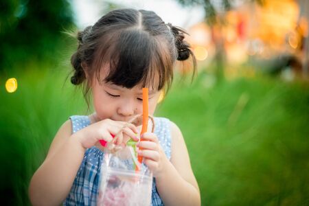 Asian little girl drinking juiceの写真素材