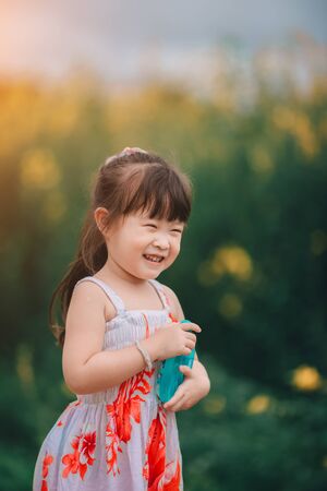 Happy little asian girl in flower fieldの写真素材