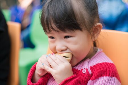 Asian little girl eating breadの写真素材