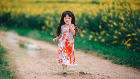Happy little asian girl in flower fieldの写真素材