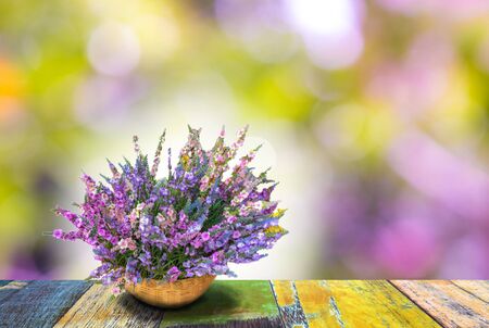 brunch of flowesr on weaving pot on colorful wooden floor with colorful bokehの写真素材