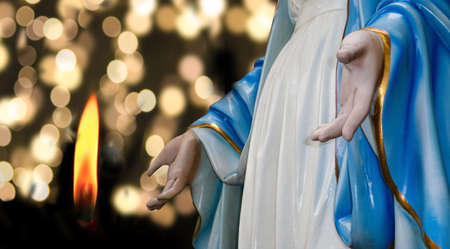 Saint Mary statue with light candle burning brightly and bright bokeh background,religion,mother of Jesus,の写真素材