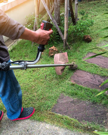 man woorker cutting the grass in garden using lawn trimmer , stay at home concept,