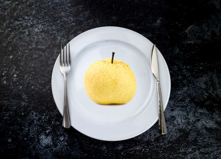 The fork and knife with fresh pear fruits on the white plate . Table setting,  juicy fruit,の写真素材