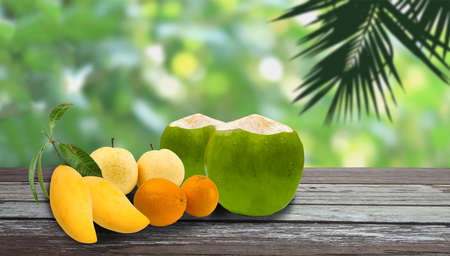 group of asian tropical fruit such as oranges , pear,  coconut,mango on wooden floor with silhouette...