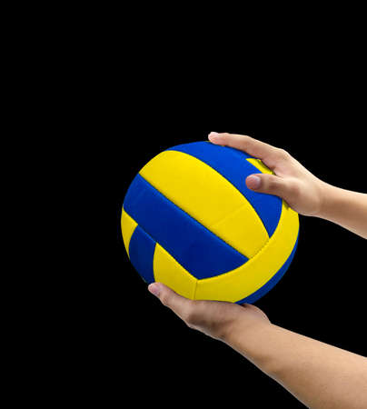 Volleyballplayer holding a ball with his arm over black background, close up image of volleyball in hands on black,sport concept,の写真素材