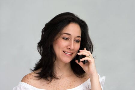 A beautiful latina lady calling on a cell phone, isolated on whiteの写真素材