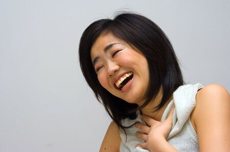 Beautifull Oriental woman in a white collared shirt laughingの写真素材