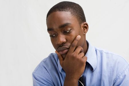 Dark skinned young business professional with hand on chin, MBA student, or such, isolated on whiteの写真素材