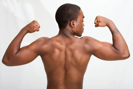 A handsome dark skinned guy showing his back and muscles in his biceps, isolatedの写真素材