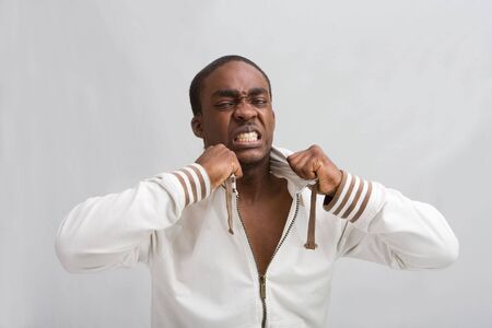 Dark skinned handsome young man, grabs his stylish white hooded shirt; Very angry! Isolatedの写真素材