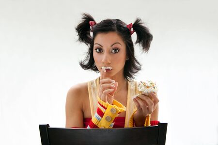 Beautiful Latina girl eating a cupcake with her fingers, isolatedの写真素材