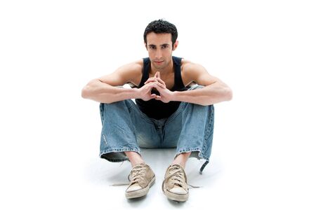 Handsome Caucasian guy wearing black tank top and jeans sitting on floor thinking, isolatedの写真素材