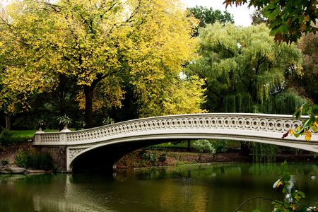 Beautiful fall autumn scenery landscape of a white bridge over a peaceful body of water lake river.の写真素材