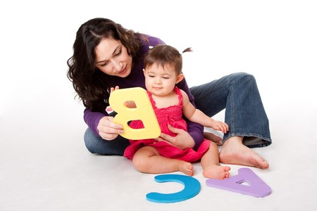 Mother, nanny, or teacher teaching happy baby to learn alphabet, A, B, C, with letters in a playful way, while sitting on floor.の写真素材
