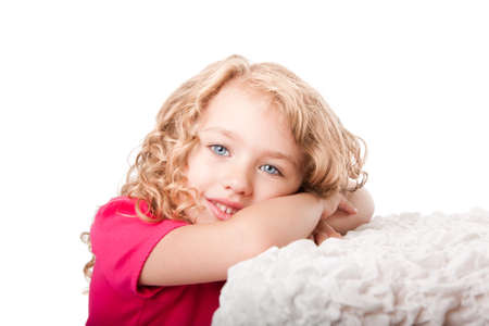 Beautiful cute happy smiling girl with blue eyes daydreaming laying on soft surface, isolated.の写真素材