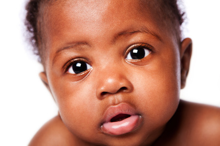 Closeup of cute adorable beautiful face of African baby with innocent expression, on white.の写真素材