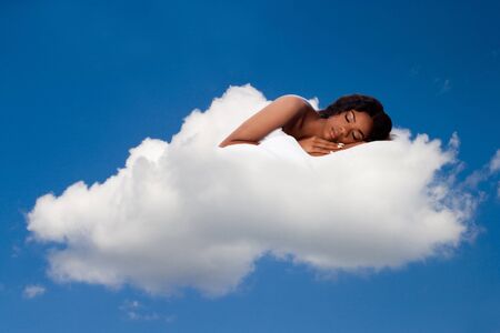 Beautiful woman deeply asleep and dreaming on comfortable soft fluffy white cloud nine, concept.の写真素材