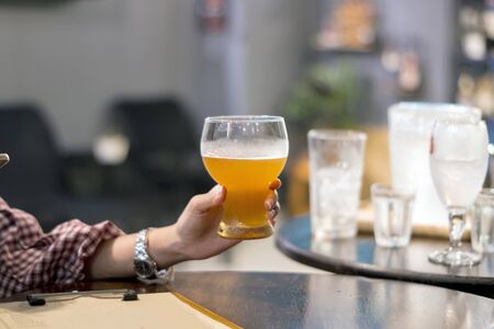 Hands holding Beer glasses clinking in bar or pub on table with food